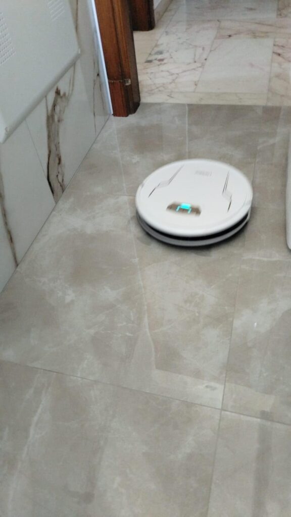 Robot aspirapolvere con spazzole che pulisce il pavimento in casa.