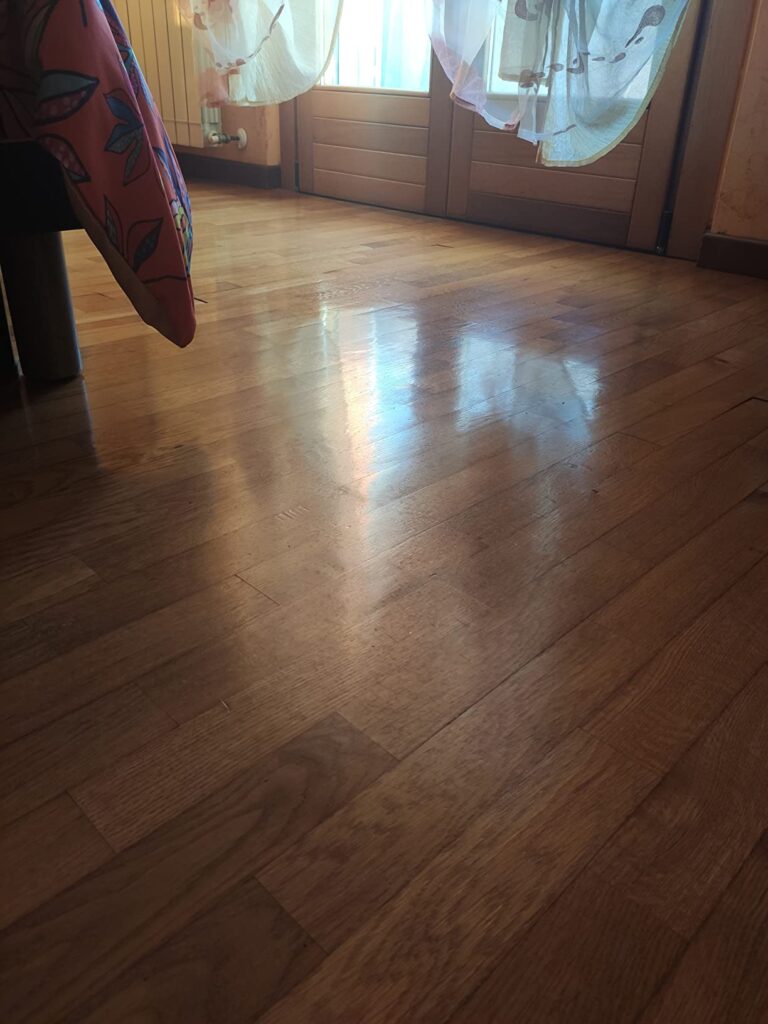 Pavimento in legno lucido vicino a porta e finestra.