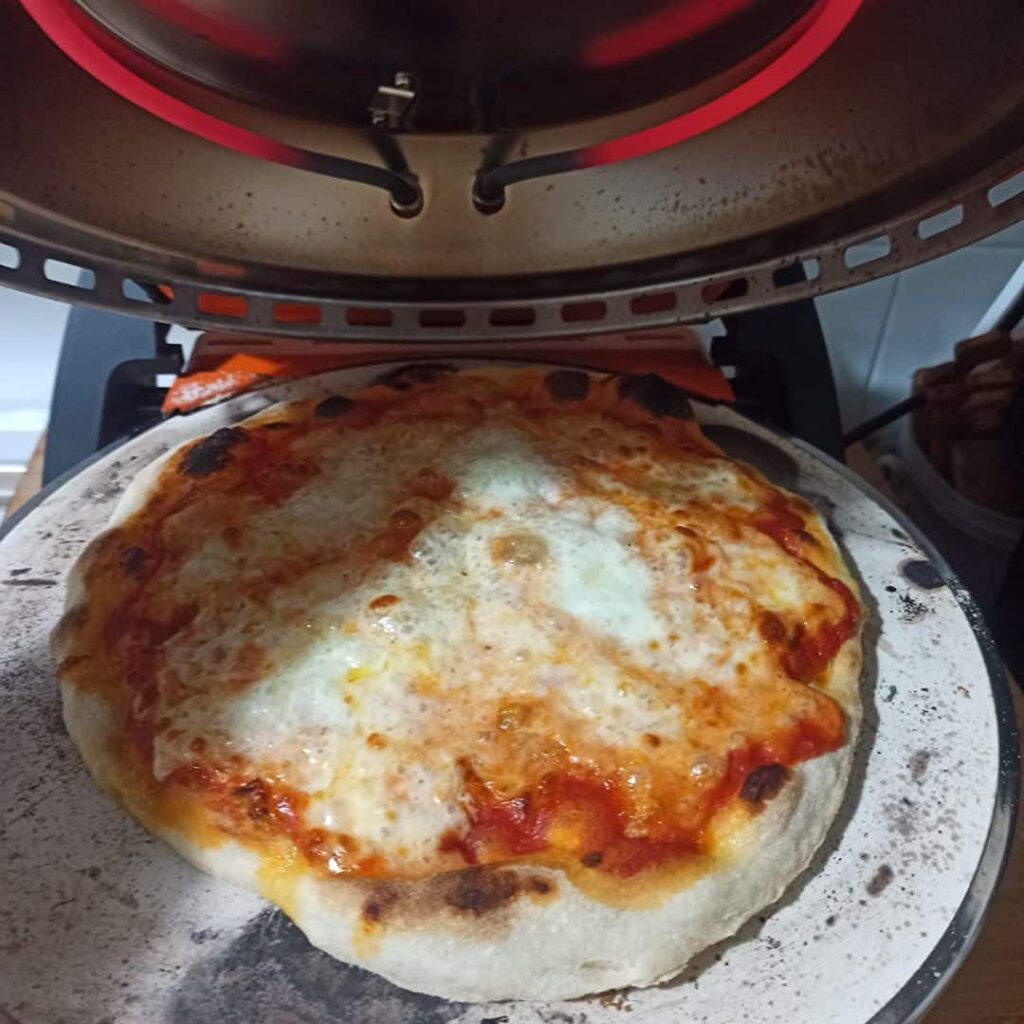 Pizza margherita calda appena sfornata nel forno a legna.