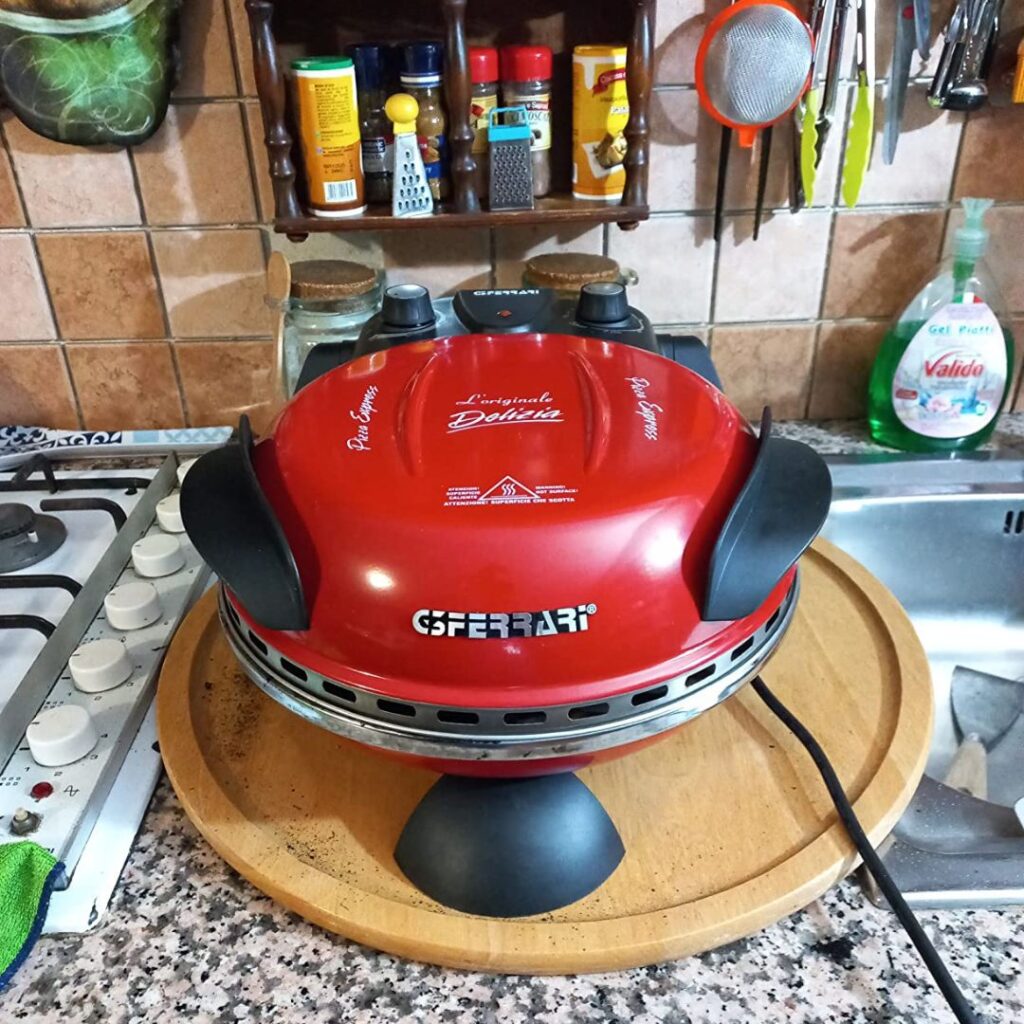 Grill a gas Ferrari rosso su piano di legno in cucina.