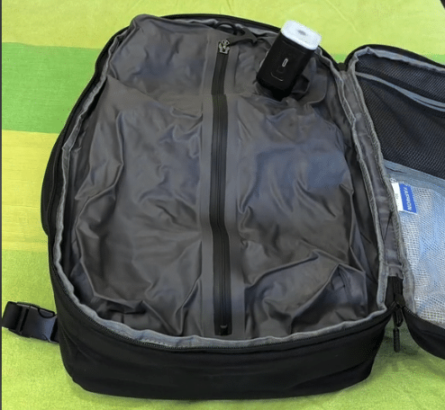 Zaino da viaggio aperto con tasche e oggetti all'interno.
