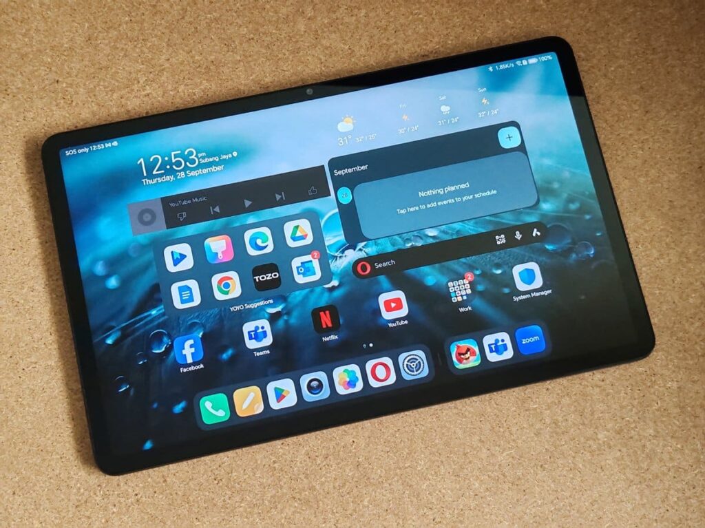 Tablet con schermo acceso, notifiche e widget meteo in primo piano.