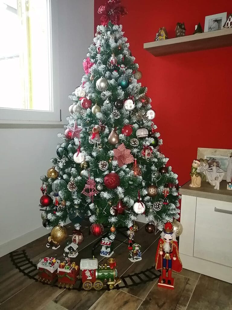 Albero di Natale decorato con pigne, luci e ornamenti colorati.